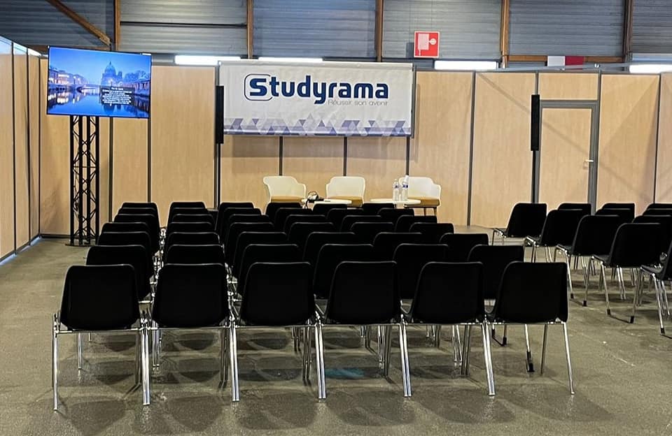 Salon d'expo Studyrama, Paris, 8 octobre 2022, avec chaises noires, écran et espace de présentation.