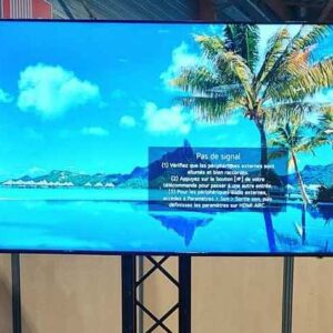 Écran affichant un message d'erreur "Pas de signal" lors d'un salon d'expo à Paris, entouré de décorations modernes.