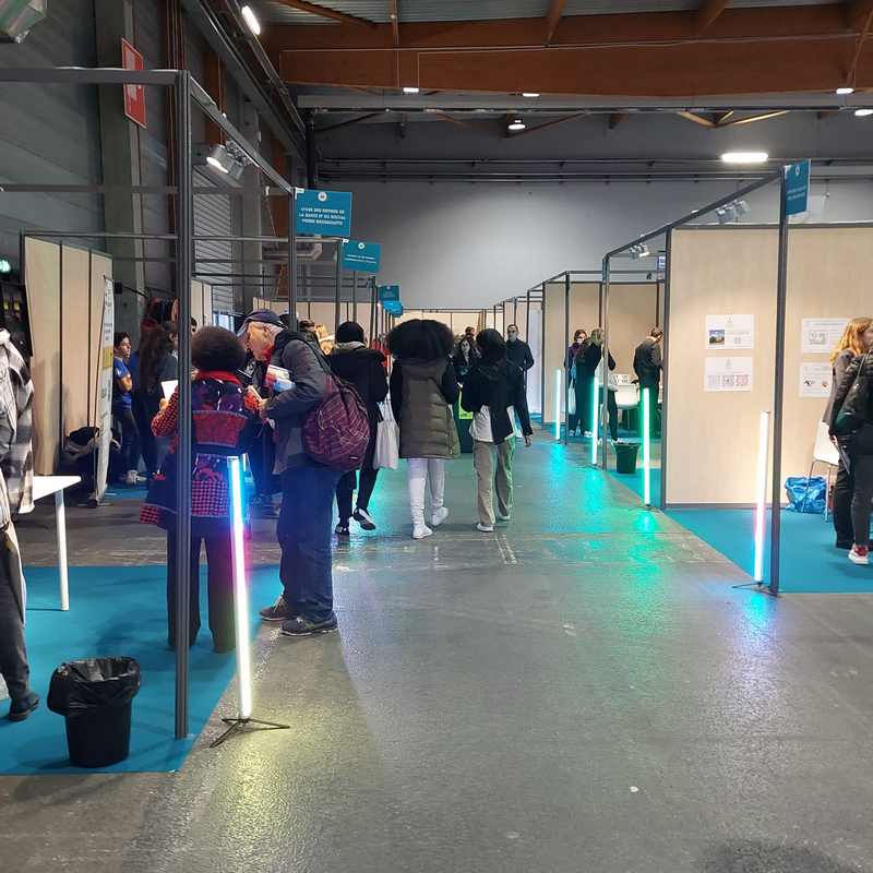 Visiteurs interactant dans un salon d'expo à Paris, avec des stands et un éclairage coloré.