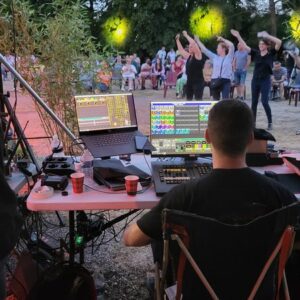 Technicien gérant l'éclairage et le son lors d'un concert pour Murex à Paris, avec un public dansant en arrière-plan.