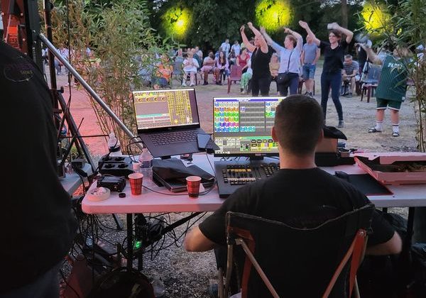 Technicien gérant l'éclairage et le son lors d'un concert pour Murex à Paris, avec un public dansant en arrière-plan.