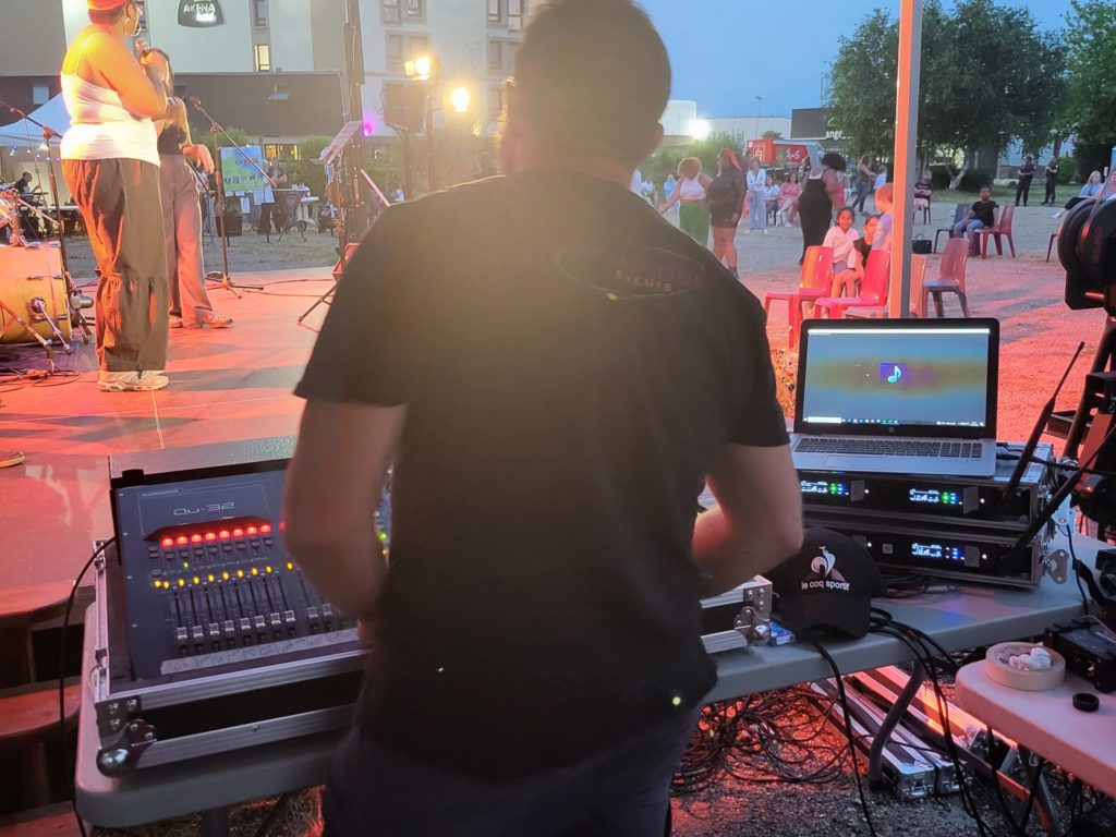 Technicien au mixage lors de la fête de la musique à Coignières, le 21 juin 2023, avec matériel de sonorisation en arrière-plan.