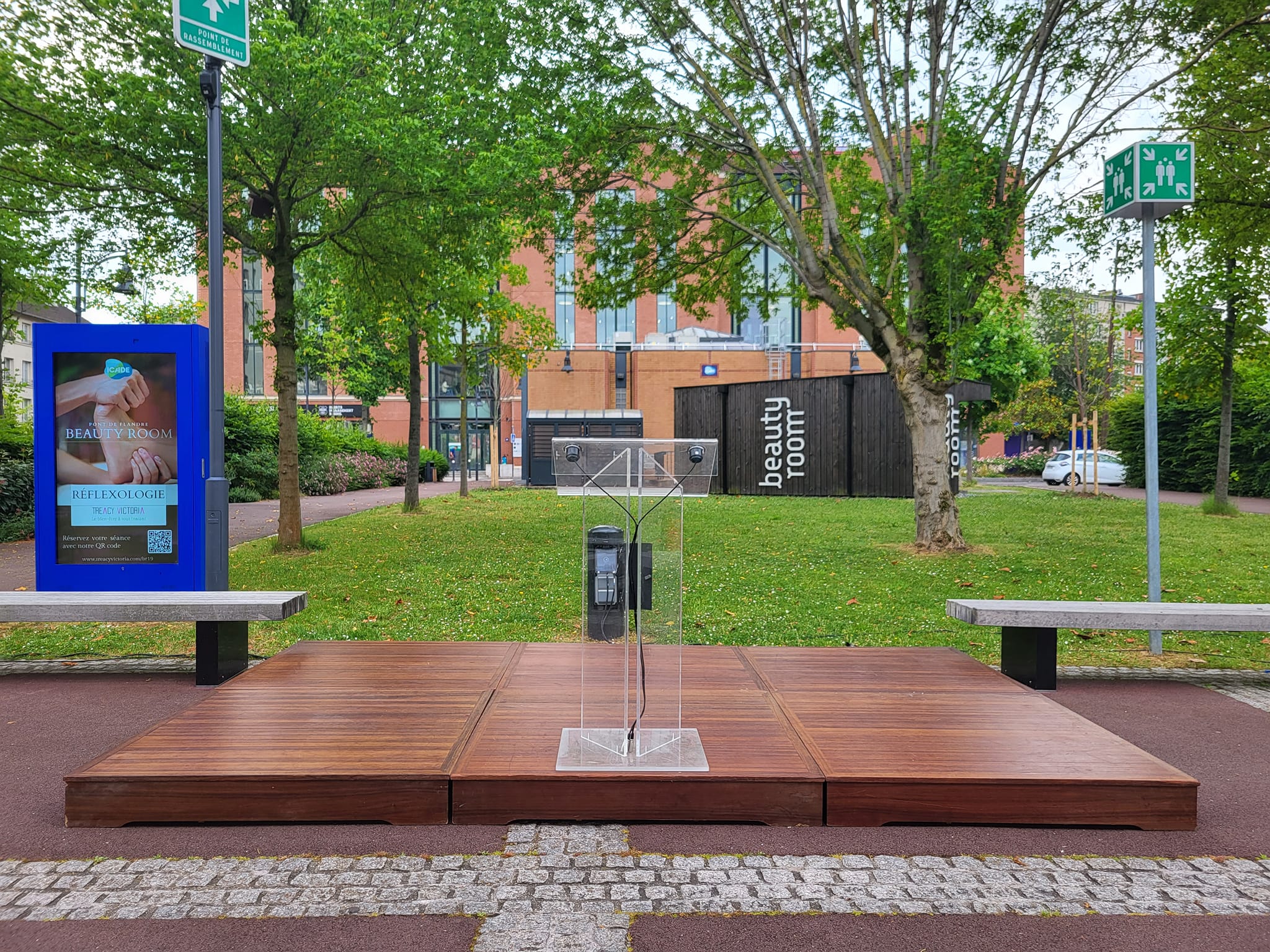 Installation d'une scène avec estrade et panneau "Beauty Room" dans un parc, prête pour un événement.