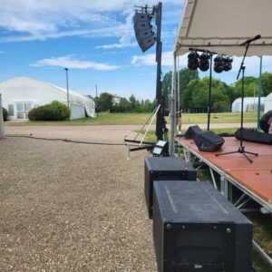 Installation de matériel de sonorisation sur scène pour un événement extérieur à Mantes-la-Jolie, juillet 2023.