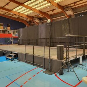 Scène de 70 m² avec pendrillon de 14 m, installée par Symbiose Organisation dans une salle de sport.