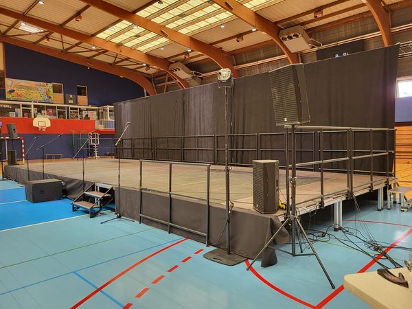 Scène de 70 m² avec pendrillon de 14 m, installée par Symbiose Organisation dans une salle de sport.
