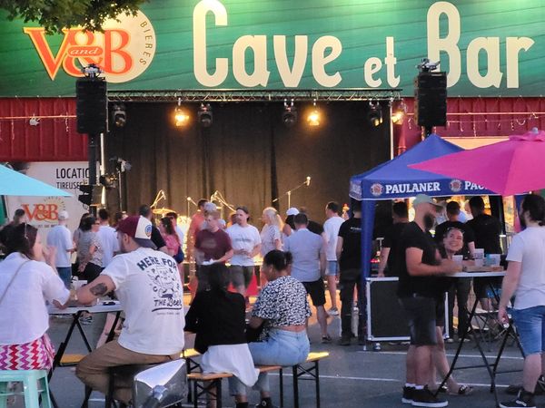 Foule animée lors de la Fête de la musique au VandB de Coignières, le 25 juin 2023, avec scène et stands colorés.