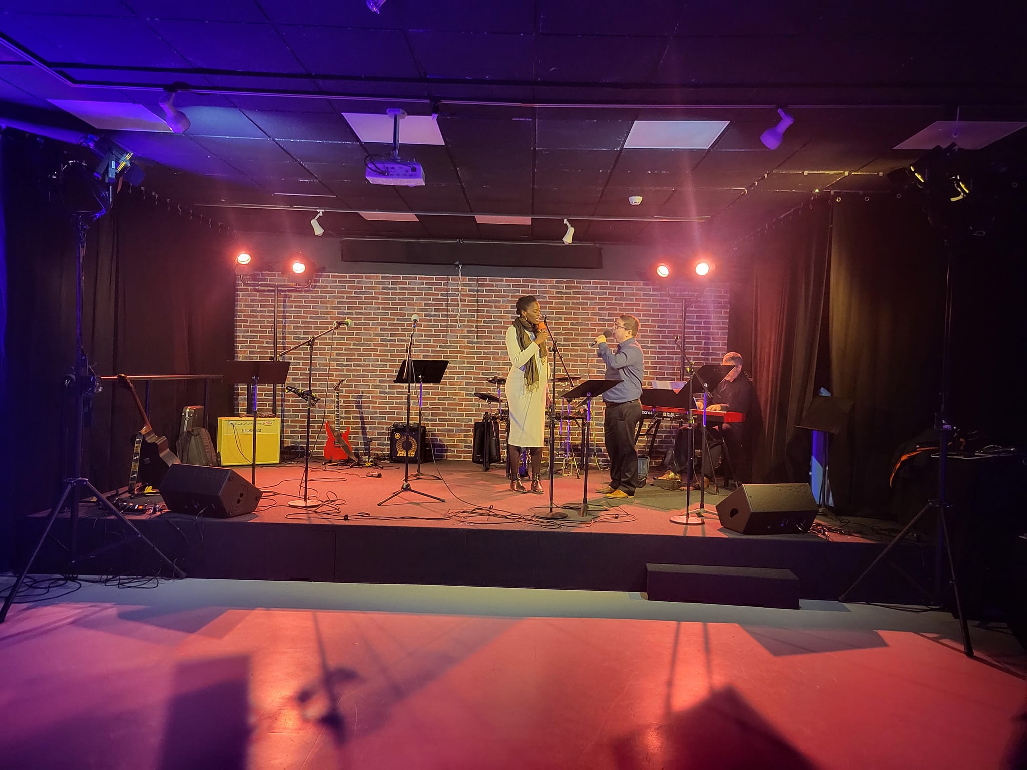 Scène avec deux artistes en pleine prestation, éclairage coloré et instruments de musique en fond, événement Safran à Vélizy-Villacoublay.