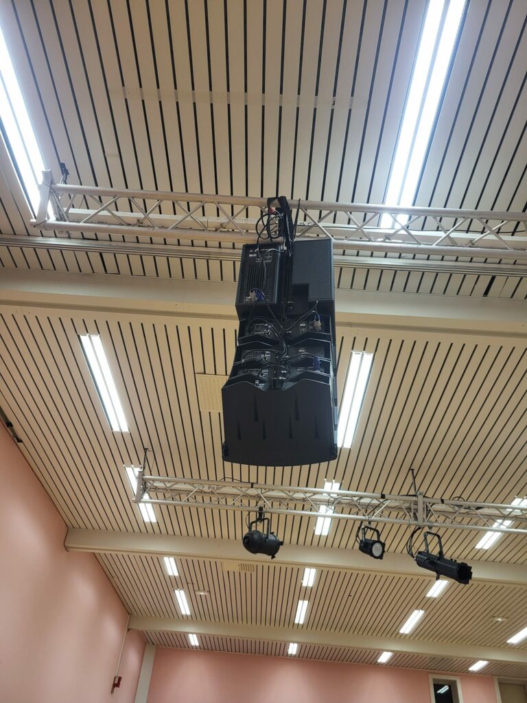 Système de sonorisation installé au Théâtre Michel Audiard à Chevreuse, avec éclairage suspendu et structure métallique.