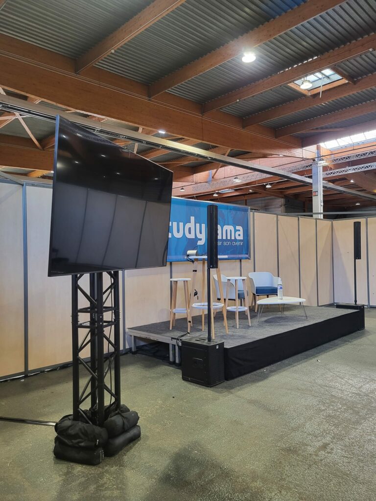 Scène de conférence au salon Studyrama, avec écran, sièges et matériel de sonorisation.