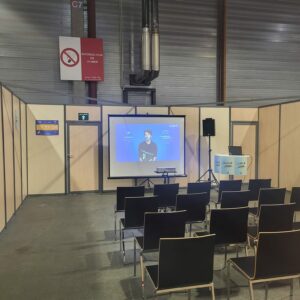 Salle de conférence à l'événement Studyrama à Paris avec chaises noires et écran de projection. Interdiction de fumer affichée.