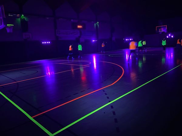 Match de basketball en lumière UV, ambiance colorée et dynamique, le 2 février 2024. Événement par Symbiose Organisation.