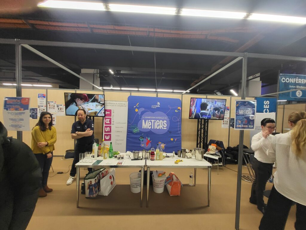 Stand d'exposition à l'Espace Champerret, avec des participants, des démonstrations et des présentations sur les métiers.