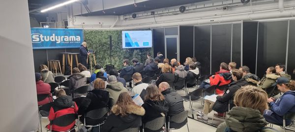 Audience attentive lors d'une présentation à l'événement Studyama, avec un intervenant sur scène.