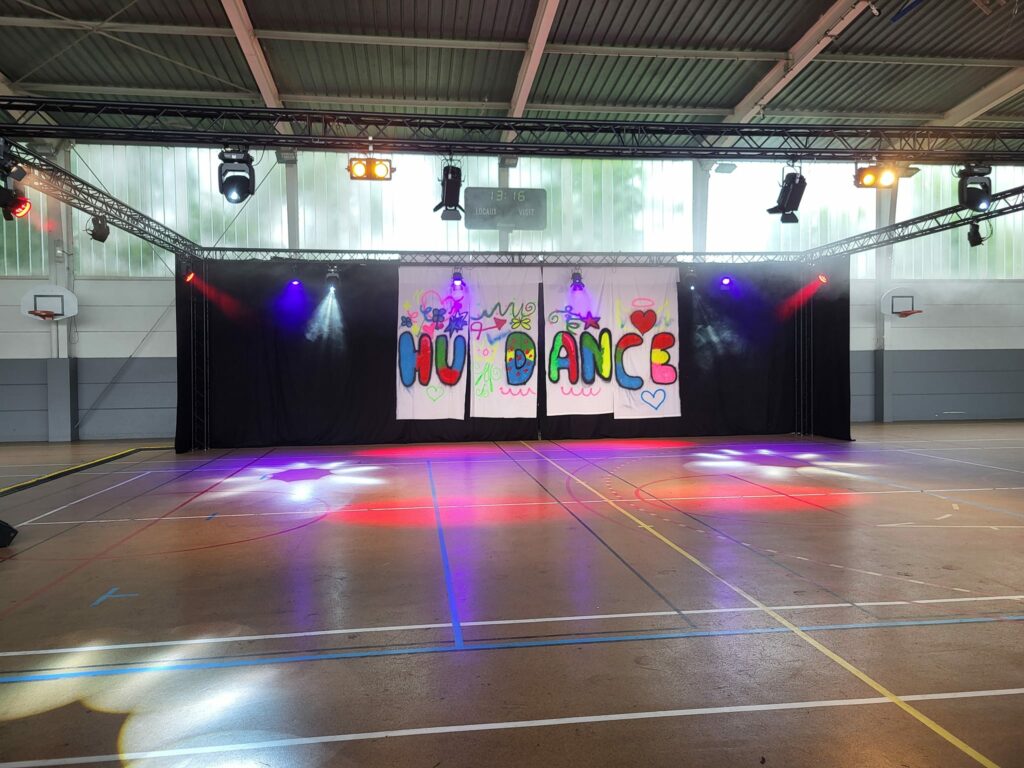 Installation du gala de danse à Houdan, avec éclairage coloré et décoration sur scène, le 01 juin 2024.