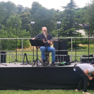 Musicien sur scène avec guitare, préparatif d'un événement en plein air aux Clayes-sous-Bois, sonorisation en cours.