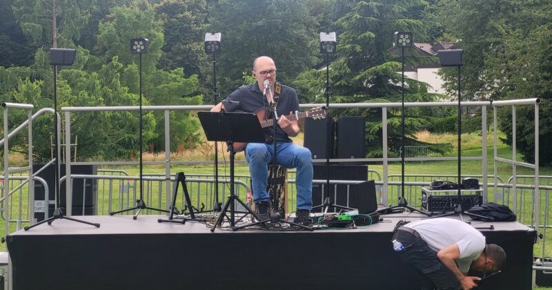 Musicien sur scène avec guitare, préparatif d'un événement en plein air aux Clayes-sous-Bois, sonorisation en cours.