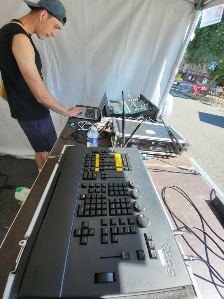 Technicien réglant la console de sonorisation pour l'installation de l'événement à Saint-Cyr l'École, juillet 2024.