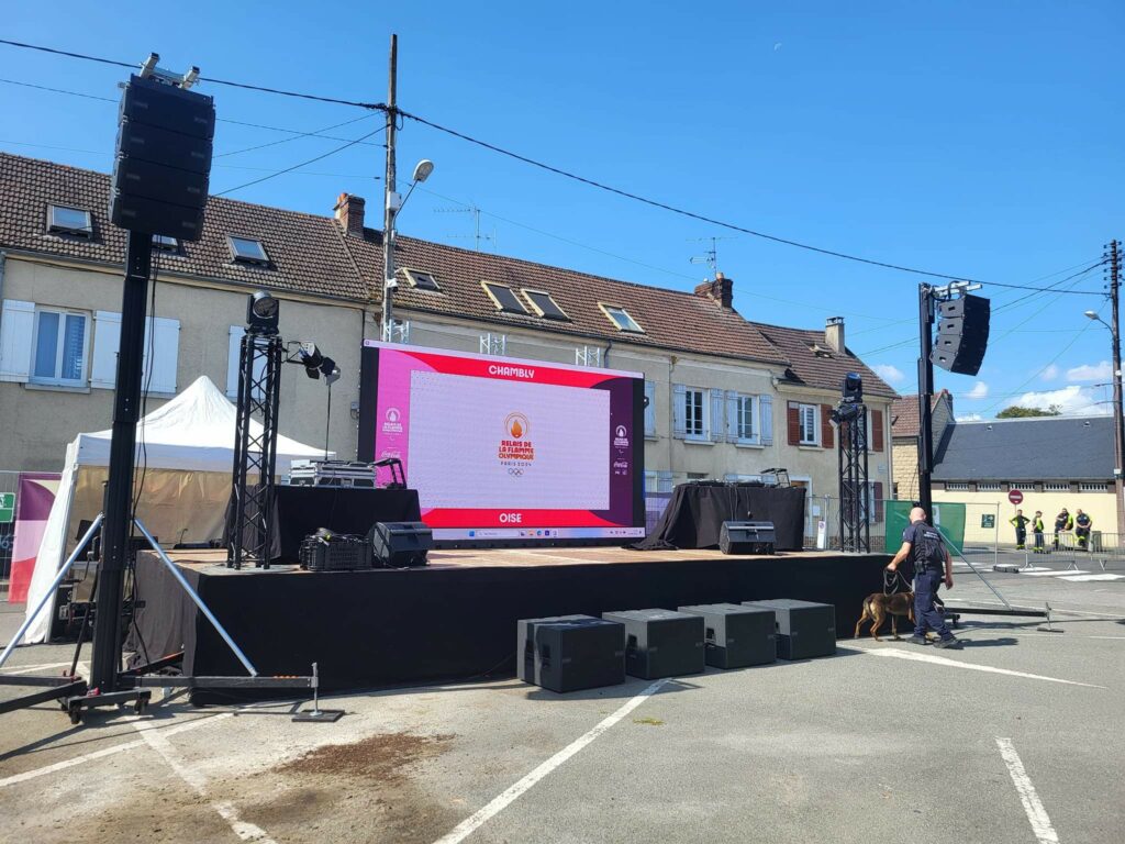 Installation de sonorisation pour la flamme Paralympique de Chambly, incluant écran, haut-parleurs et équipements professionnels.