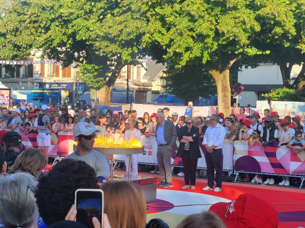 Installation de la sonorisation pour la flamme Paralympique de Chambly, avec une foule rassemblée autour d’une scène.