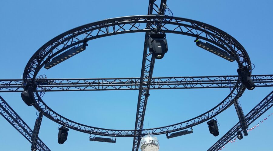 Système d'éclairage suspendu avec projecteurs et boule à paillettes, installé pour un événement extérieur.