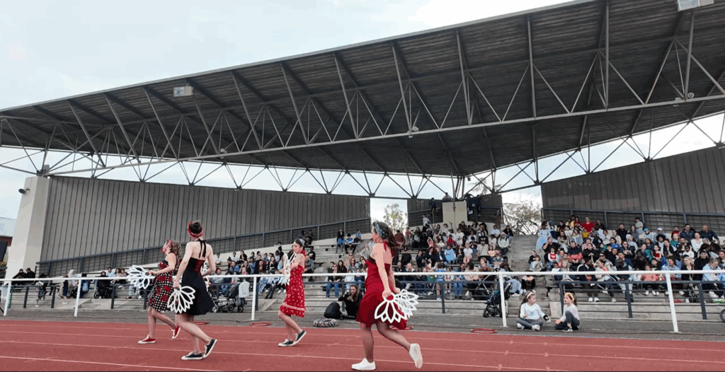 Des danseurs en costumes colorés exécutent une performance devant un public enthousiaste dans un stade pour la fête du Sport.