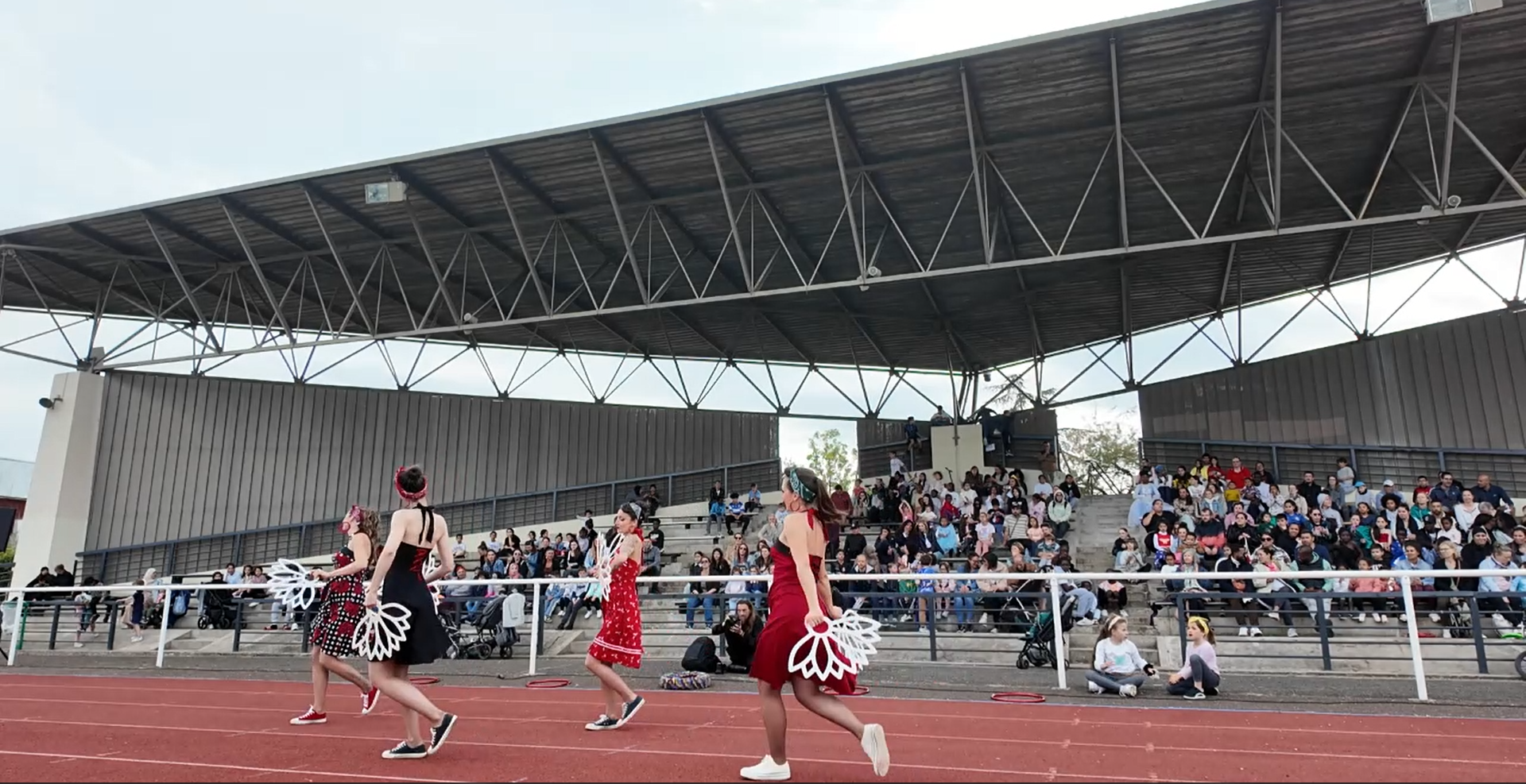 Des danseurs en costumes colorés exécutent une performance devant un public enthousiaste dans un stade.