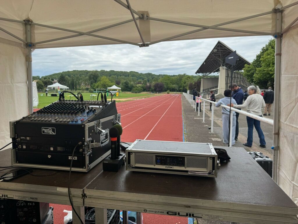 Equipement de son et éclairage installé pour un événement en plein air sur une piste d'athlétisme.