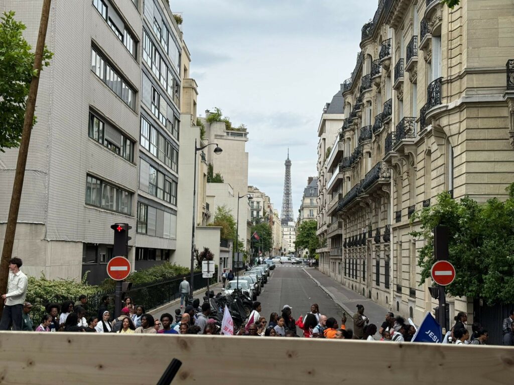 Vue d'une rue à Paris avec des manifestants, l'Eiffel Tower en arrière-plan.
