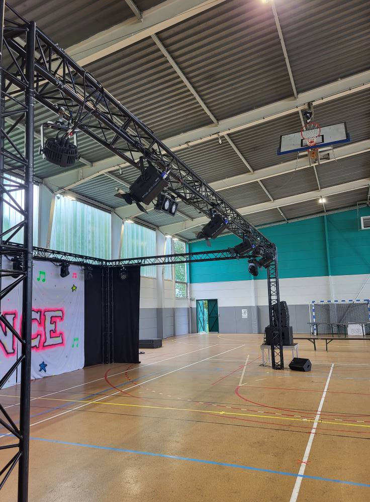 Installation de matériel de son et d'éclairage pour un événement dans une salle polyvalente.