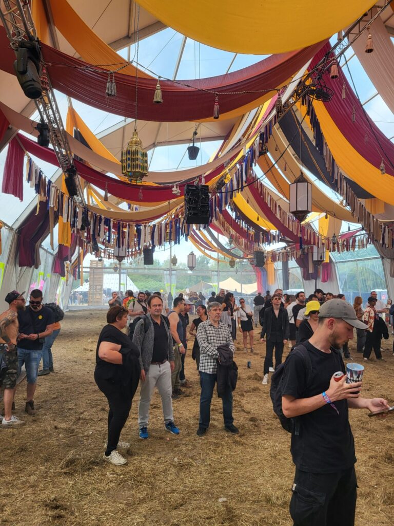 Intérieur festif avec un plafond décoré et une foule appréciant l'événement. Ambiance conviviale et musicale.