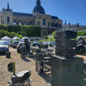 Matériel de sonorisation et éclairage de Symbiose Organisation installé en extérieur, avec un bâtiment historique en arrière-plan.