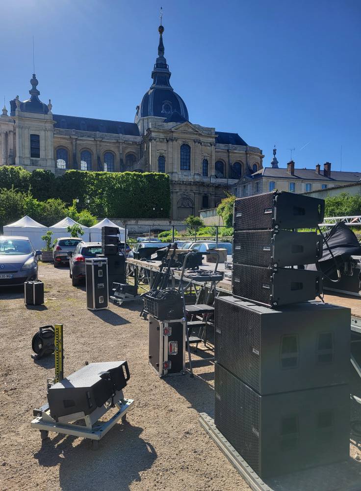 Matériel de sonorisation et éclairage de Symbiose Organisation installé en extérieur, avec un bâtiment historique en arrière-plan.