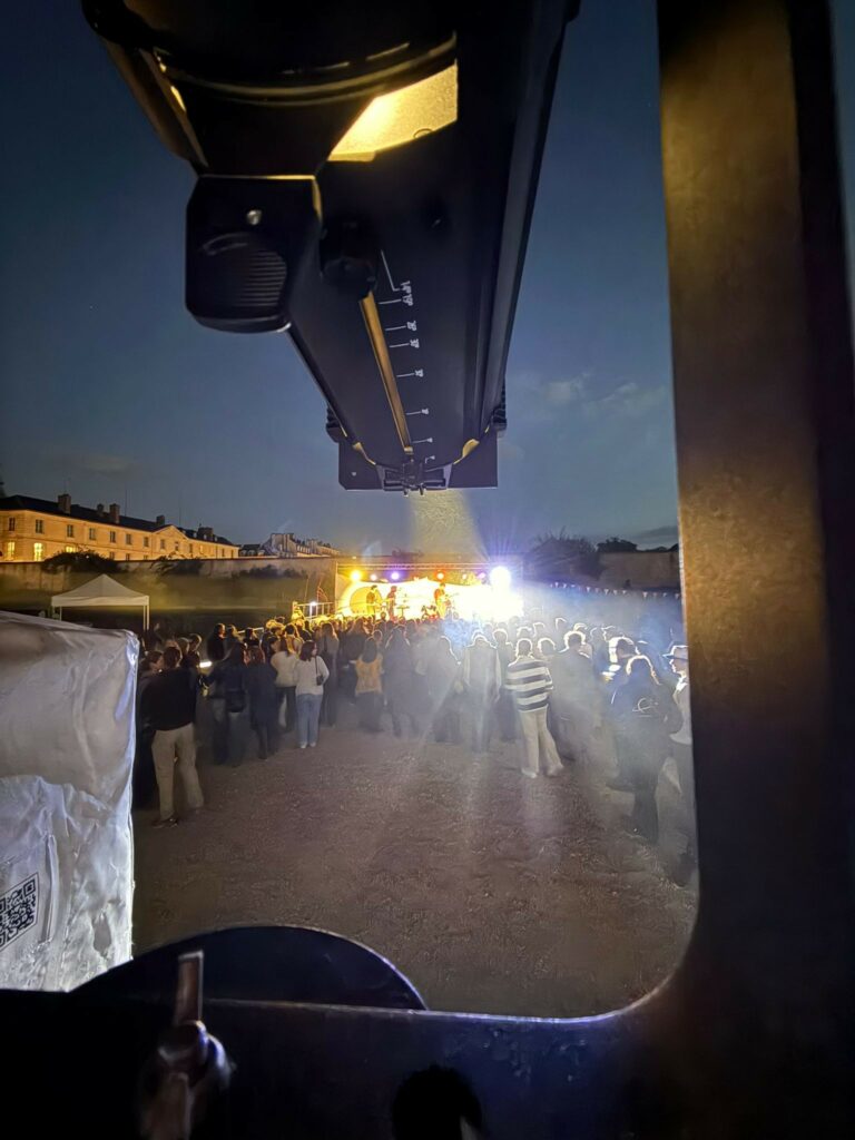 Vue de matériel d'éclairage sur un public lors d'un événement nocturne avec des lumières vives en arrière-plan.
