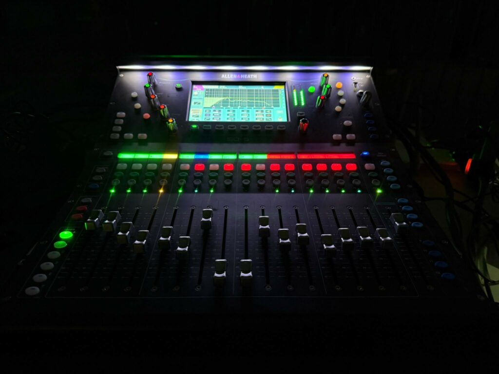 Table de mixage professionnelle avec commandes lumineuses multicolores. Utilisée pour sonorisation et éclairage.