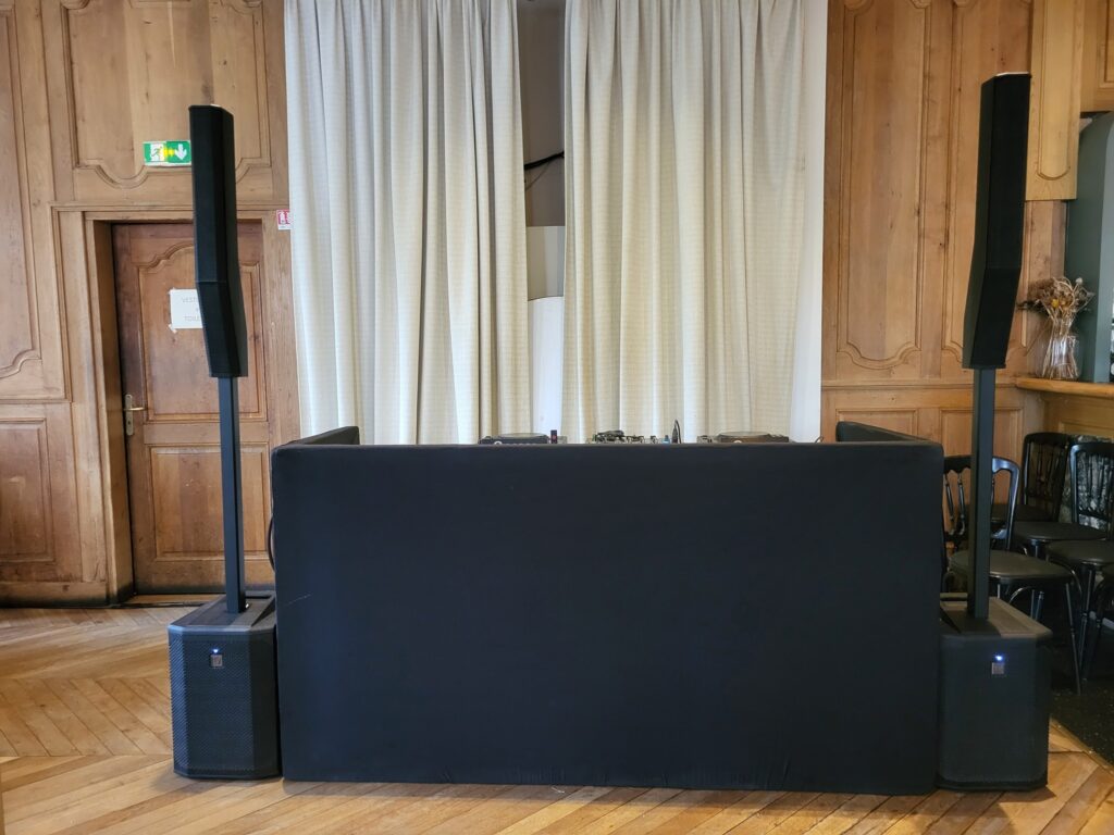 Installation de matériel de sonorisation avec deux enceintes et une console, dans un espace événementiel.