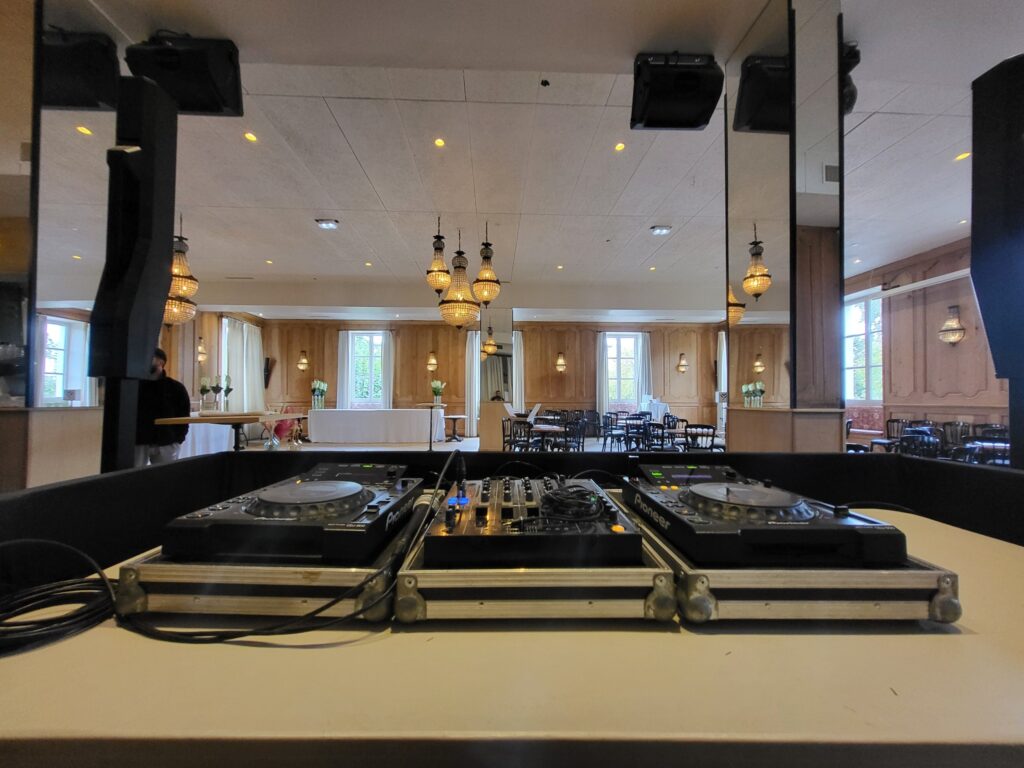 Poste de DJ avec équipements de sonorisation, vue d'une salle d'événement élégante.