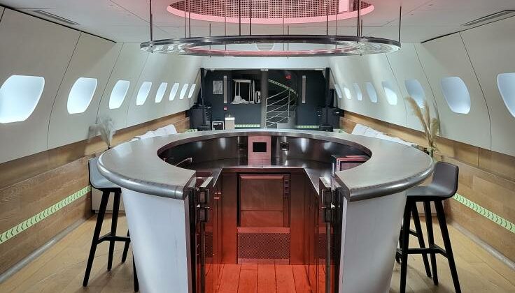 Intérieur d'un espace moderne avec comptoir circulaire, éclairage d'ambiance rose et sièges, conçu pour des événements.