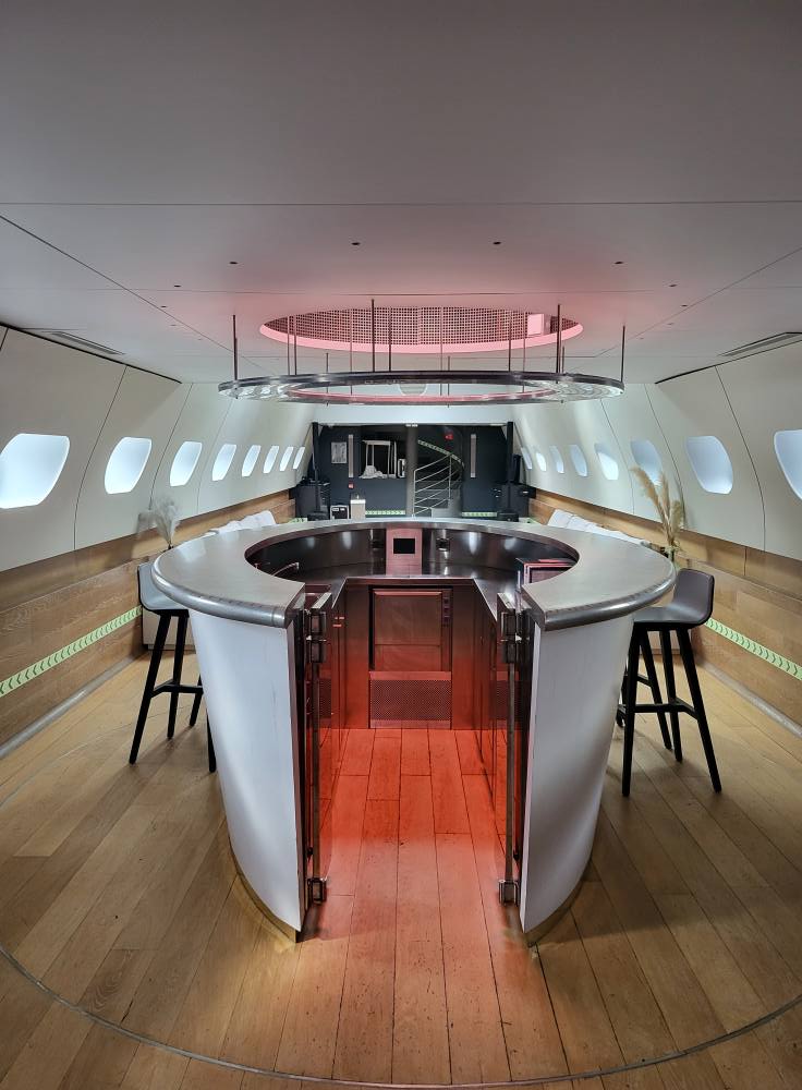 Intérieur d'un espace moderne avec comptoir circulaire, éclairage d'ambiance rose et sièges, conçu pour des événements.