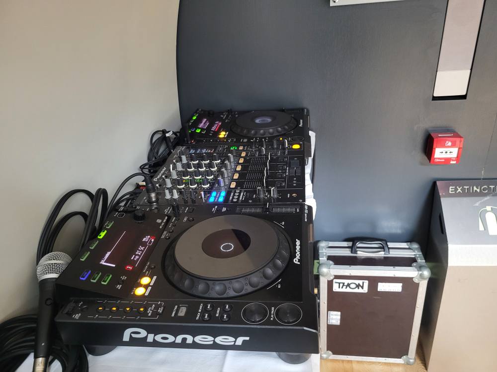 Table de mixage Pioneer avec contrôleurs, câbles et microphone, prête pour une installation sonore.
