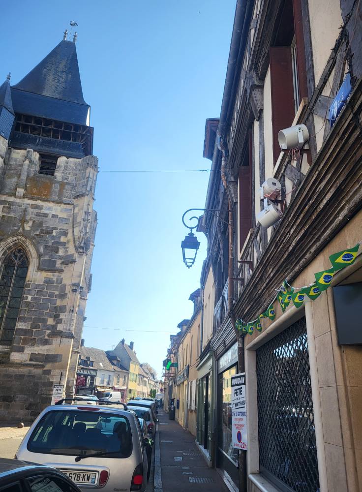 Vue d'une rue avec bâtiments historiques, panneaux d'animation et matériel de sono installés sur les façades.