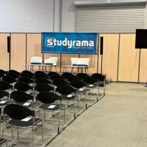 Salle de conférence avec chaises en rangées, podium, écran et bannière "Studyrama".