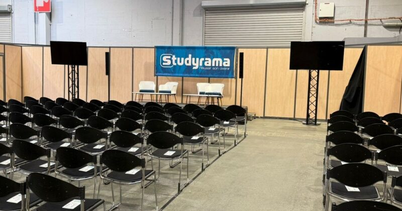 Salle de conférence avec chaises en rangées, podium, écran et bannière "Studyrama".