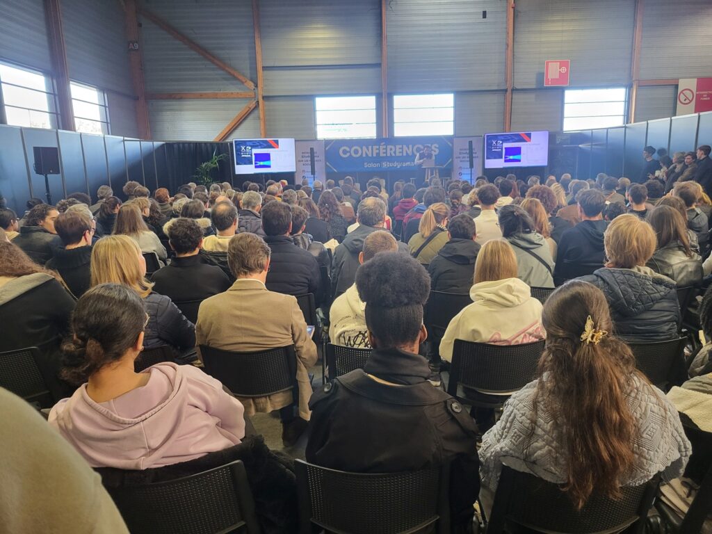 Une foule attentive assiste à une conférence, mettant en avant des présentations sur le son et l'éclairage.