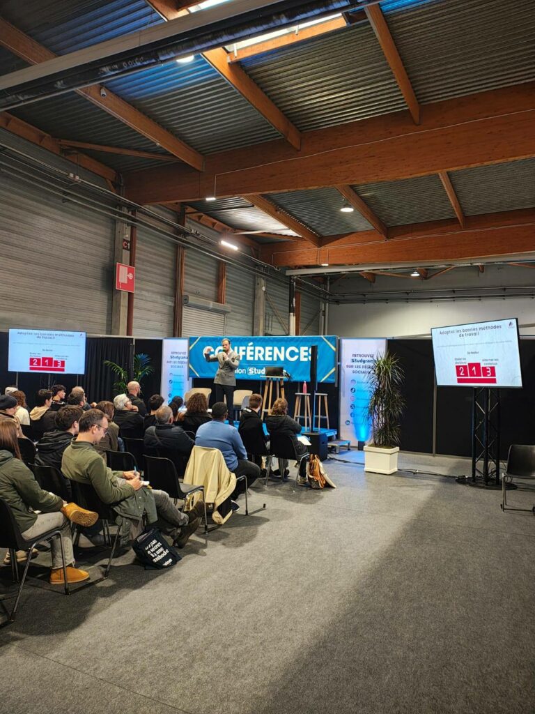 Conférence animée sur les méthodes de travail, avec un orateur devant un public attentif, organisée par Symbiose Organisation.