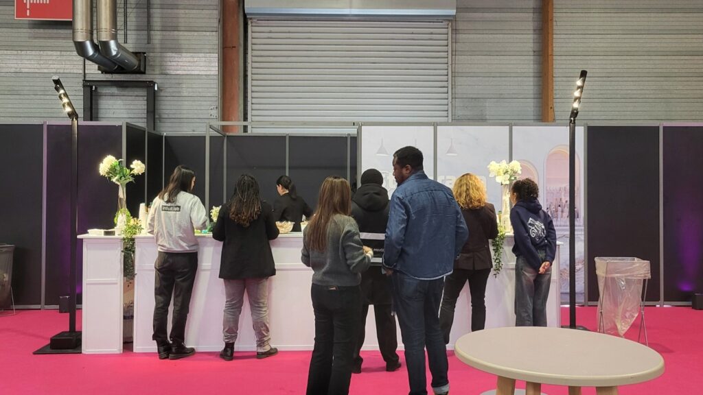 Groupe de personnes au comptoir d'un événement, attendant avec des éléments de décoration florale en arrière-plan.