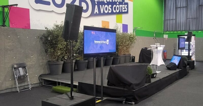 Installation de matériel de sono et éclairage pour un événement, avec écrans et scène décorée.