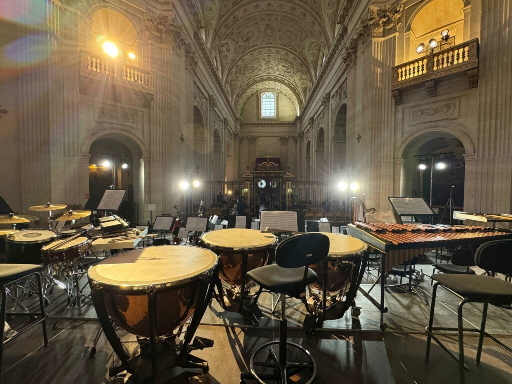 Vue d'un espace de concert avec des instruments de percussion en premier plan, éclairage en arrière-plan.