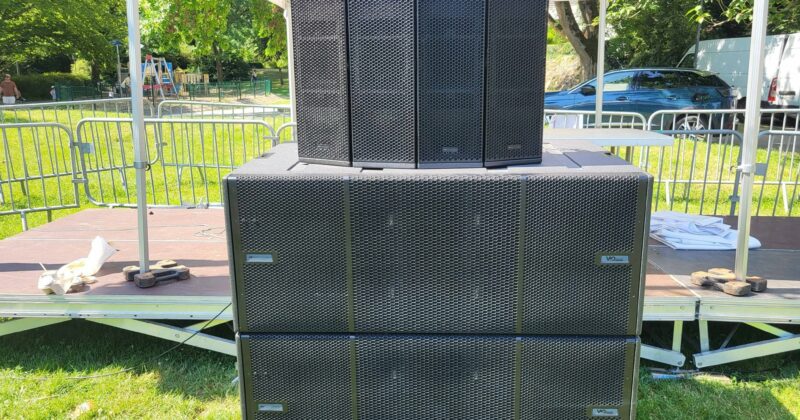 Système de sonorisation installé sur scène, avec plusieurs haut-parleurs en grille noire.