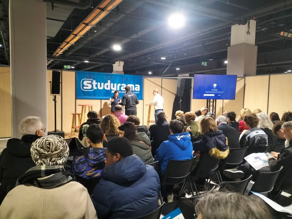 Public présent lors d'un événement organisé par Studyrama, avec des intervenants sur scène. Équipement audio et visuel en arrière-plan.